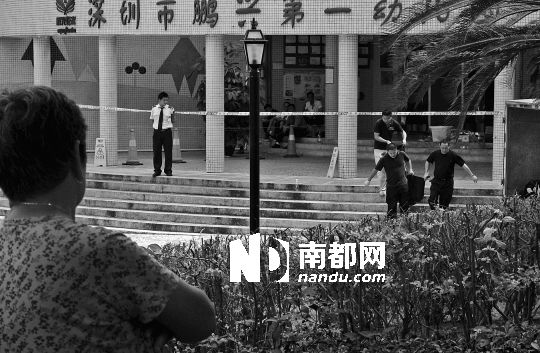 →7月19日，鵬興花園第一幼兒園門前，民警在現(xiàn)場進(jìn)行完勘查取證后，園長和保安的尸體被運(yùn)走。南都記者 徐文閣 攝