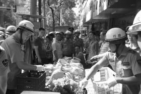7月11日，瀏陽市北正中路，執(zhí)法人員暫扣張海的水果。這是瀏陽市城管局拍攝的執(zhí)法現(xiàn)場圖。
