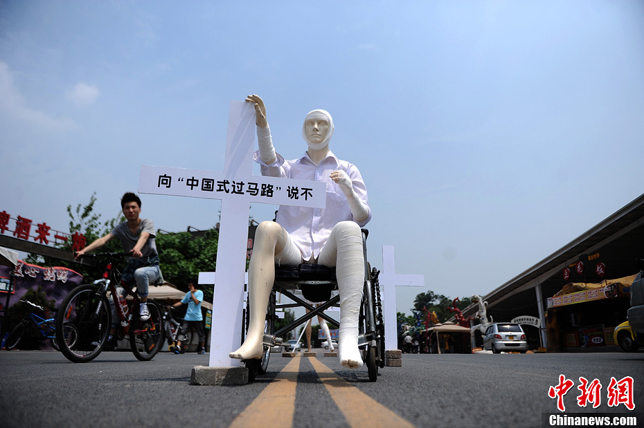 4月16日，重慶市洋人街上擺放著兩個(gè)受了傷的塑料人像“模特”，旁邊十字架上寫(xiě)著向“中國(guó)式過(guò)馬路”說(shuō)不