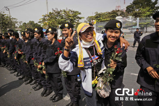 2013年12月03日,曼谷總理府與曼谷警署允許反政府示威民眾進入,雙方進入暫時“停戰(zhàn)”狀態(tài)迎接泰王生日。曼谷警察總署,女警們手持鮮花送給反政府示威民眾。圖片來源:Manish Swarup/東方IC