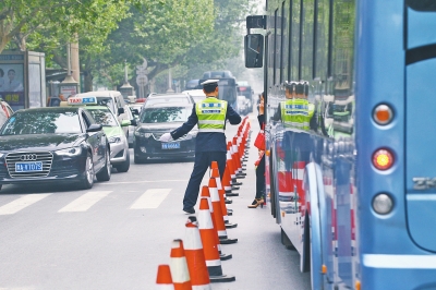 省人民醫(yī)院南門的路中間擺放反光錐，交警示意由西向東車輛從前方繞行。