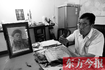 　魏樹紹手拿《物權法講義》手稿，在講訴先祖書寫“物權法”的歷史（相框里就是魏聯(lián)奎）