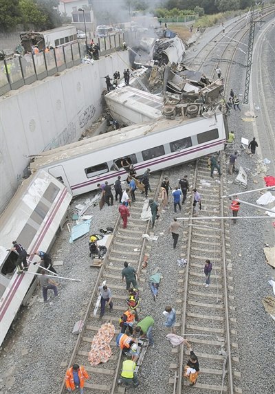 24日，救援人員在西班牙列車脫軌現(xiàn)場。一節(jié)車廂被強大的慣性拋上鐵道邊的高臺。