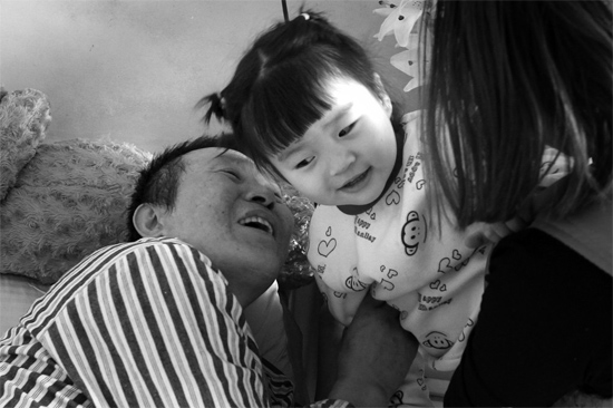 病床前李剛父女倆說著“悄悄話”，幸福的氣氛洋溢在病房中
