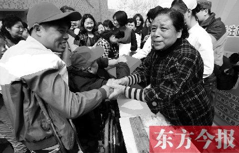 昨日，鄭大四附院的大樓前，“面人鄭”鄭玉芬（右）向前來捐款的殘疾人表示感謝