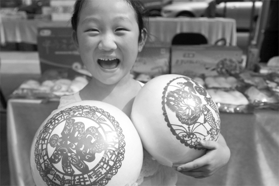 在2013河南食品安全宣傳周活動(dòng)現(xiàn)場(chǎng)，一個(gè)小女孩抱著參展的特色大饅頭樂開了花