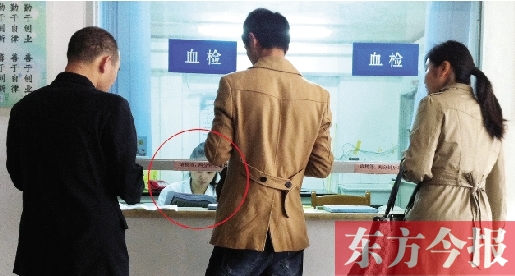 昨日，鄭州市二七區(qū)疾控中心辦證大廳，血檢窗口內(nèi)一名女工作人員，邊接受辦證者咨詢邊看報(bào)紙