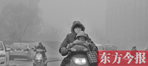 12月8日，鄭州市未來(lái)路上，一位市民帶著孩子在霧中騎行