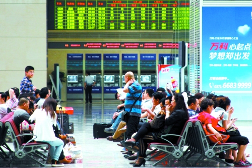 候車大廳溫度很高，一名乘客一手扇風(fēng)、一手擦汗
