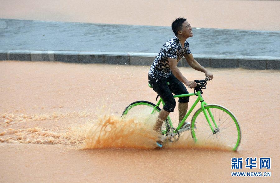 5月11日，一名行人在深圳街頭冒雨騎行。