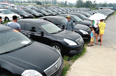 昨日，市民在山東棗莊一家拍賣公司場地上查看待拍賣公車。當(dāng)日，棗莊市103輛公車公開拍賣。新華社記者