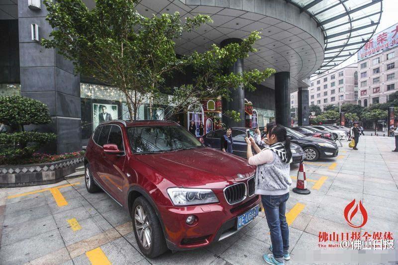 一輛停在停車位上的寶馬轎車，被墜落的樹枝砸中，樹枝徑直插入車內(nèi)，現(xiàn)場引發(fā)不少市民圍觀拍照。